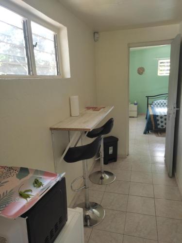 Habitación con escritorio y mesa con 2 taburetes en SOFT YLaNG en Dembeni