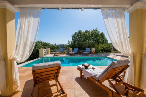 a patio with a pool and two chairs and a table at Red Rose Artistsvillas in Gaios