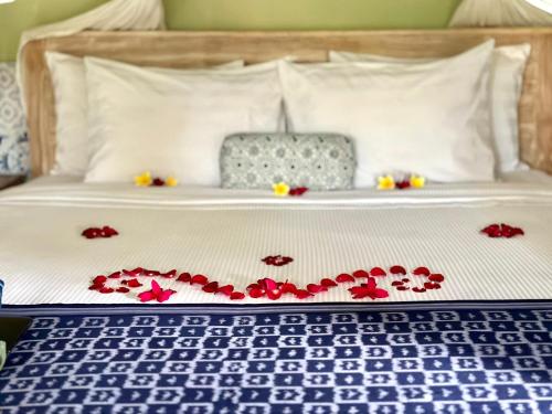 a bed with red rose pedals on it at Umah Arya Homestay in Gianyar