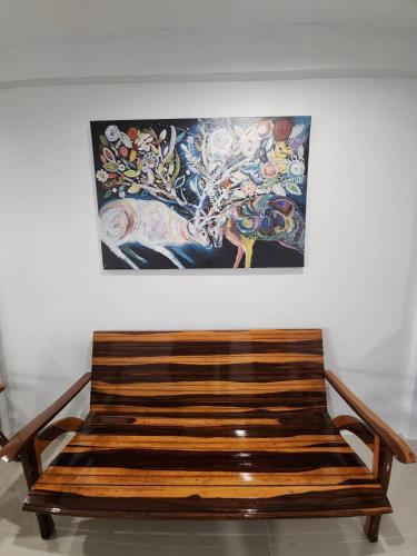 a wooden bench in front of a painting on a wall at No.9 Hostel kanchanaburi in Ban Don Rak