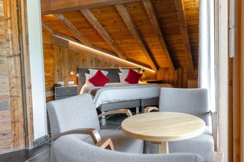 a room with two beds and a table and chairs at Hôtel Alpina & SPA - Restaurant Oxalis in Les Gets