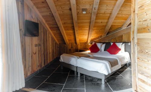 a bedroom with a bed in a wooden ceiling at Hôtel Alpina & SPA - Restaurant Oxalis in Les Gets