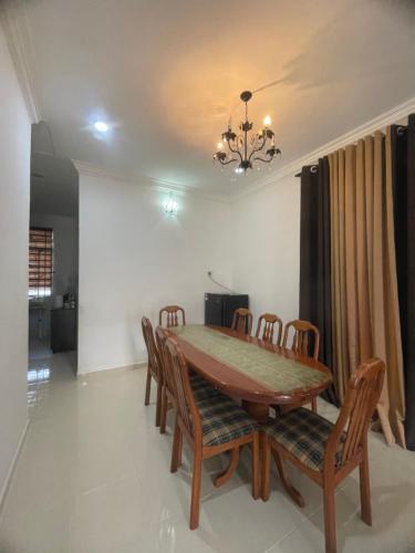 Homestay Cendana Gong Badak في Kampong Tanjong Gelam: غرفة طعام مع طاولة وكراسي خشبية