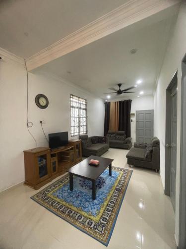 a living room with a coffee table and a couch at Homestay Cendana Gong Badak in Kampong Tanjong Gelam