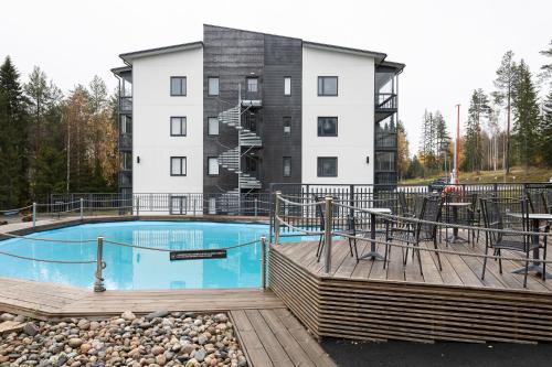 una piscina con terraza y un edificio en Vuokatti Booking Suites, en Vuokatti