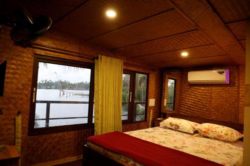 a bedroom with a bed and a large window at Riverine Homestay Kochin in Ernakulam