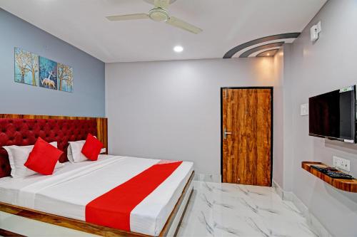 OYO Tara Maa Guest House في كولْكاتا: غرفة نوم بسرير على اللوح الأمامي الأحمر وتلفزيون