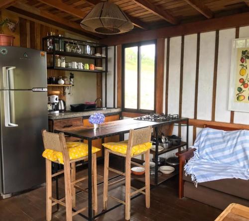 a kitchen with a table with chairs and a refrigerator at Pescador de Sonhos in Praia do Rosa