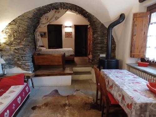 a room with a stone archway with a bed and tables at Baita del Plan in Pragelato
