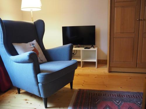 una silla azul en la sala de estar con TV en Traditional house in the heart of La Roche-Bernard, en La Roche-Bernard