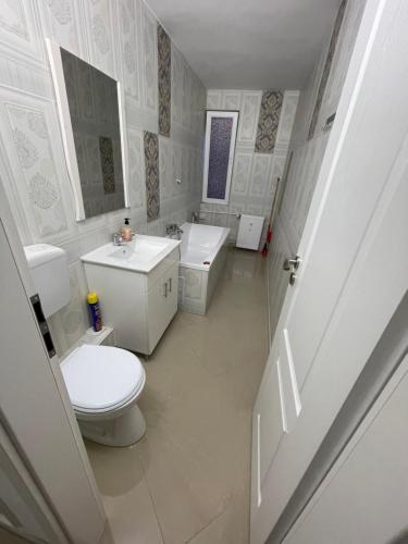 a white bathroom with a toilet and a sink at Garsoniera Cristina in Bucharest