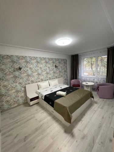 a bedroom with a large bed and a room with chairs at Garsoniera Cristina in Bucharest