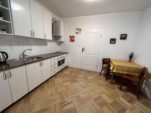 a kitchen with white cabinets and a table and a sink at Pokoje Gościnne Impresja Kadzidło in Kadzidło