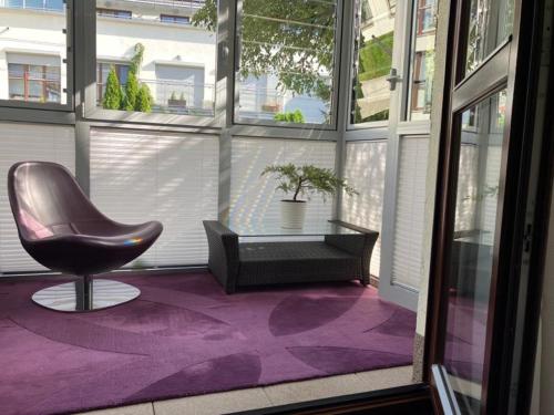 a chair sitting on a purple rug in a room with windows at Royal Place 2 bedrooms Apartment Wilanów in Warsaw