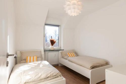 a white bedroom with two beds and a window at Ostseeparadies mit Garten, 3 Zimmer, strandnah in Scharbeutz