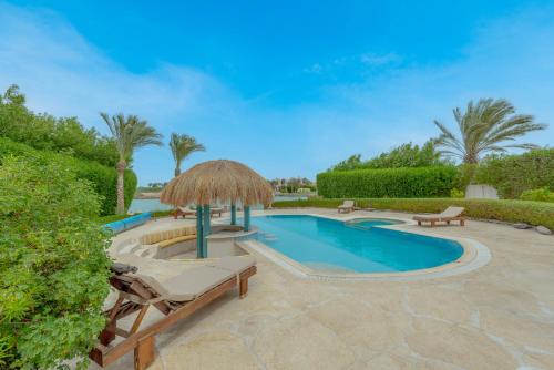 basen ze słomianym parasolem i szezlongami obok w obiekcie Stunning Villa for Rent in El Gouna HEATED PRIVATE POOL w mieście Hurghada