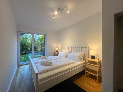 a white bedroom with a large bed and a window at LIBORIA I Stylisches Haus I Sauna I Wellness in Starnberg