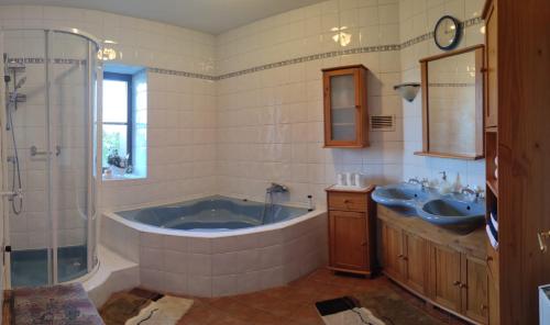 łazienka z 2 umywalkami, wanną i prysznicem w obiekcie Die Hube w mieście Leutschach