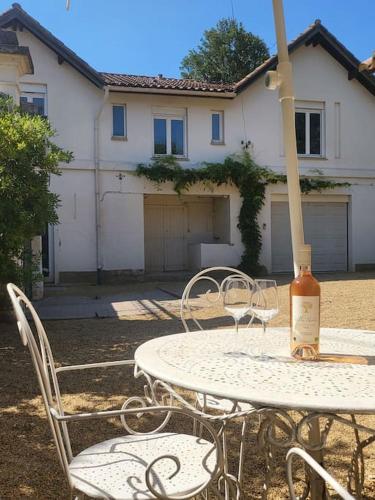 - une table et des chaises avec une bouteille de vin dans l'établissement Villa les Tilleuls - Arènes de Béziers, à Béziers