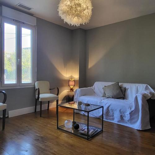 - un salon avec un canapé, une table et un lustre dans l'établissement Villa les Tilleuls - Arènes de Béziers, à Béziers