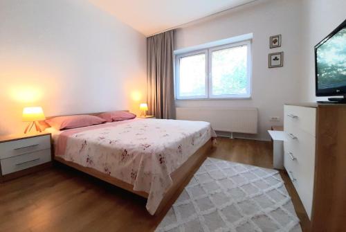 a bedroom with a bed and a flat screen tv at Central Modern Apt with Garden in Struga