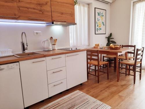 cocina con armarios blancos y mesa de madera en Central Modern Apt with Garden, en Struga