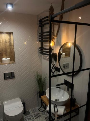 a bathroom with a sink and a toilet and a mirror at Nowoczesny mały Apartament nr 3 nad jeziorem in Orzysz