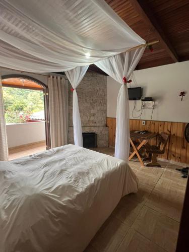 a bed with a canopy in a room with a fireplace at Chalés & Casas Shallon Adonai in Visconde De Maua