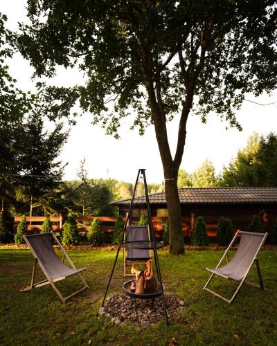 two chairs and a fire pit in a yard at TO TU Chańcza Duży Domek in Raków