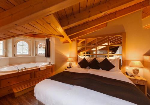 a bedroom with a large bed and a bath tub at Hotel Albatros in Zermatt