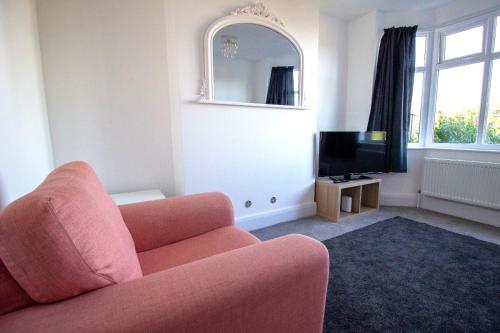 a living room with a pink couch and a tv at Fully renovated spacious home, Sleeps 5, in Grantham