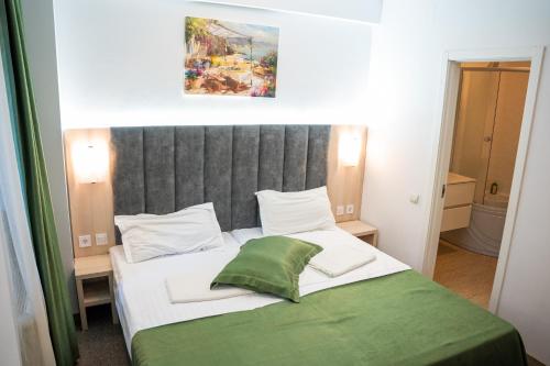 ブカレストにあるHotel Cantemirのベッドルーム1室(大型ベッド1台、緑の毛布付)