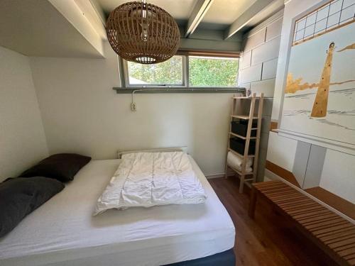 - une petite chambre avec un lit et un lustre dans l'établissement Wildrijk 104, à Sint Maartensvlotbrug