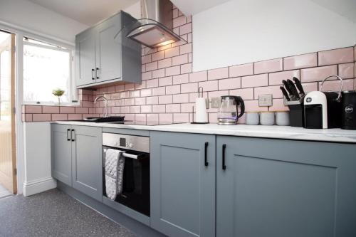 a kitchen with white cabinets and a black oven at Maindy House - Home close to City Centre + parking in Cardiff