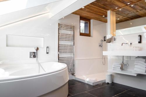 a bathroom with a white tub and a sink at Hôtel Alpina & SPA - Restaurant Oxalis in Les Gets