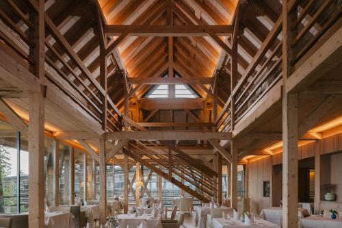 a dining room with wooden ceilings and white tables at Vigilius Mountain Resort in Lana
