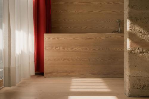 a hallway with a wooden door and a red curtain at Vigilius Mountain Resort in Lana