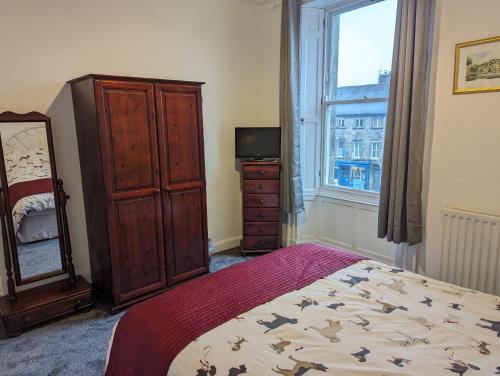 a bedroom with a bed and a dresser and a window at Market Place Flats in Barnard Castle