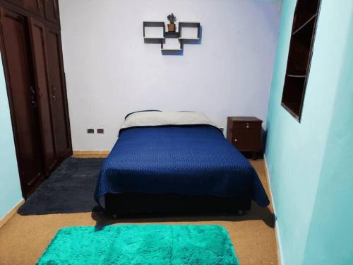 a bedroom with a bed with blue sheets and green rugs at Cálido Garzonier en Sopocachi in La Paz