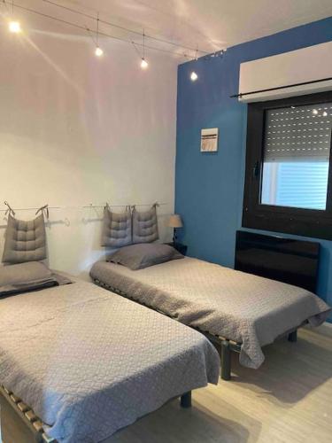 - 2 lits dans une chambre avec un mur bleu dans l'établissement Maison SAINTE LUCIE DE PORTO-VECCHIO, à Sainte-Lucie de Porto-Vecchio