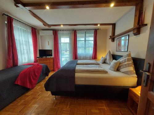 a bedroom with two beds and red curtains at Titi Family Apartman in Bük