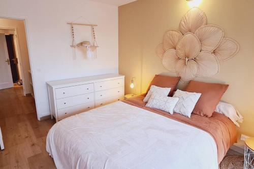1 dormitorio con 1 cama grande con una flor en la pared en Appartement neuf proche parc de Versailles + parking, en Le Chesnay