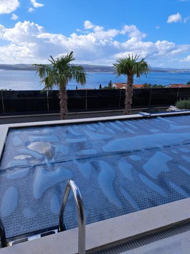 a swimming pool with a view of the ocean and palm trees at Villa Belissima Vista Mare in Selce