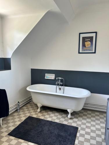 eine weiße Badewanne in einem Zimmer mit einer Wand in der Unterkunft LE PARC in Coulanges-sur-Yonne