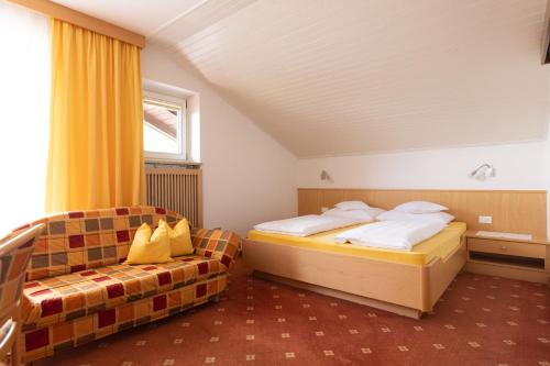 a bedroom with two beds and a couch at Garni Juval in Tirolo