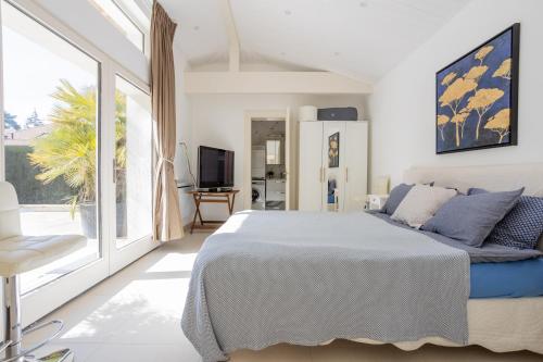 ein weißes Schlafzimmer mit einem Bett und einem großen Fenster in der Unterkunft Residence Mont-Blanc Poolhouse in Genf