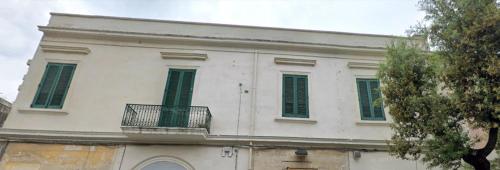 a white building with green shutters and a balcony at Vittoria Luxury House in Lecce