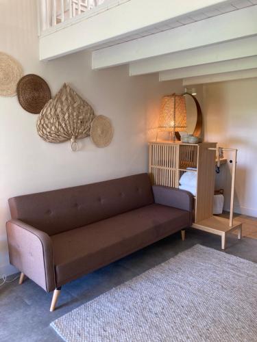 a living room with a brown couch and a mirror at Op Oost Boutique hotel & Restaurant het Kook Atelier in Oosterend