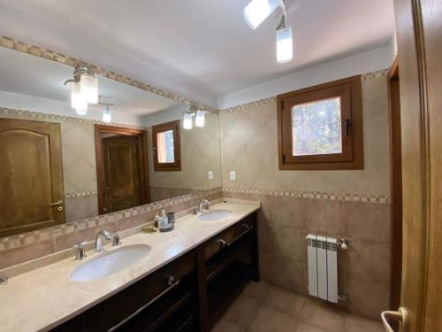 baño con 2 lavabos y espejo grande en La casa de la colina en San Carlos de Bariloche