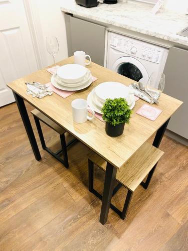a wooden table with plates and a plant on it at Buckinghamshire Elegant Studio in Buckinghamshire